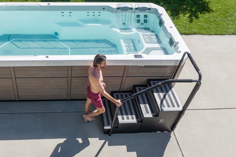 Homme montant les marches pour entrer dans le spa de nage.